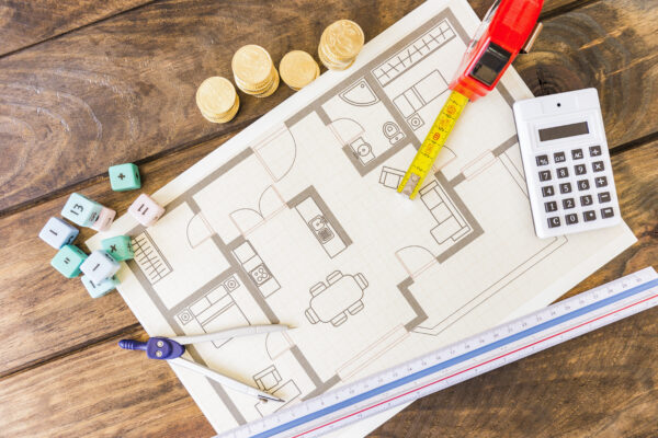 Building plans, a calculator and coins on a desk