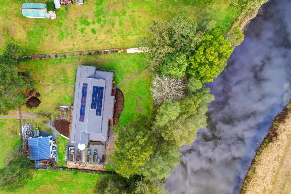 Aerial view of a modular home on a regional riverside property, showing site access and surrounding land.