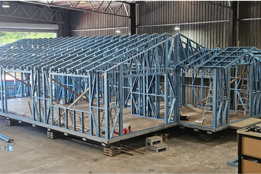 Steel wall and roof frames for modular homes under construction in the factory before transport to site.